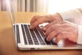 Man's hands typing on laptop keyboard.