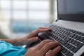 Man`s hands typing on laptop notebook keyboard in the office. Man browsing information on internet. Freelance blogging