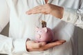 A man`s hands in a white shirt puts a one dollar bills in a pink piggy bank Royalty Free Stock Photo