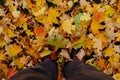 Man`s legs in boots and gray jeans standing on ground with gold autumn leaves, top view. Royalty Free Stock Photo