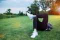 Legs in white sneakers lying on the grass at sunset time. Spring summer vacation relax concept Royalty Free Stock Photo