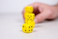 Man`s Mans Hand Stacking Up Yellow Dice in the Background