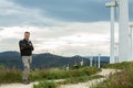 Man`s portrait outdoor against sky with wind turbine. Windmill generators. Wind power generators