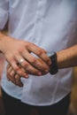 Man's right hand with a silver wedding ring and wristwatch in the left hand