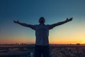 Man`s silhouette with hands rised up to sky on sunset cityscape bacground. Feeling and celebrating freedom, victory, sucsess. Exp Royalty Free Stock Photo