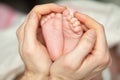 Man`s strong hand gently holds little feets newborn