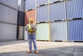 A man safety supervisor in yellow hardhat and safety vest working on laptop computer to inspect container cargo