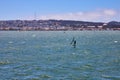 Man sailboarding on choppy San Francisco bay waters on bright summer day with city in background