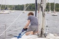 Man on sailboat tying a rope to cleat