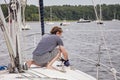 Man on sailboat tying a rope to cleat