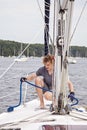 Man on sailboat tying a rope to cleat