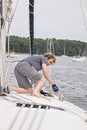 Man on sailboat tying a rope to cleat