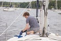 Man on sailboat tying a rope to cleat