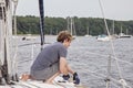 Man on sailboat tying a rope to cleat