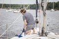 Man on sailboat tying a rope to mooring ball