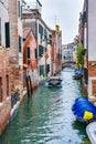 Man sailing boat on waterway/ river water canal between buildings and people traversing pedestrian bridge in background in Venice Royalty Free Stock Photo