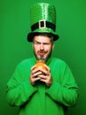 Man in Saint Patrick's Day leprechaun party hat hold Pot of gold on green background. Happy St Patricks Day concept Royalty Free Stock Photo