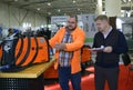 Man sales manager consulting customer about semi automatic welding machine presented on stand in the exhibition hall