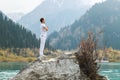 A man in a Samasthiti pose on a stone among a mountain lake Royalty Free Stock Photo