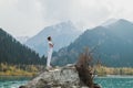 A man in a Samasthiti pose on a stone among a mountain lake Royalty Free Stock Photo