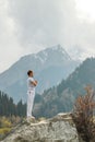 A man in a Samasthiti pose on a stone among a mountain lake Royalty Free Stock Photo