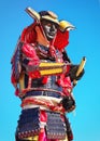 Man in samurai costume with sword on blue sky background. Royalty Free Stock Photo