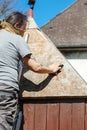 Man sanding the tin roof of his backyard shed with a sanding block Royalty Free Stock Photo