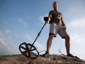 Man on a sandy ground with a metal detector looking for treasure on a sunny summer day Royalty Free Stock Photo