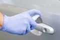 Man sanitizing door handle of his car outdoors. Male hand in protective glove holding sanitizer closeup