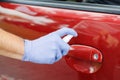 Man sanitizing door handle of his car outdoors. Male hand in protective glove holding sanitizer closeup