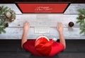 Man with a Santa Claus Christmas hat open a Christmas greeting on his computer Royalty Free Stock Photo