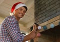 Man in Santa hat decorating fireplace with Christmas lights Royalty Free Stock Photo