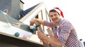 Man in Santa hat decorating house with Christmas lights Royalty Free Stock Photo