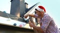 Man in Santa hat decorating house with Christmas outdoors Royalty Free Stock Photo