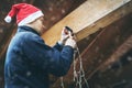 Man with santa hat decorating house outdoor carport with christmas light garland Royalty Free Stock Photo