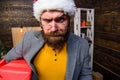 Man santa hat deliver gift. Bearded guy serious face carry present box. Delivery christmas present. Delivery service