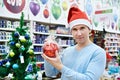 Man in Santa hat holding a red ball Christmas tree Royalty Free Stock Photo