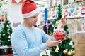 Man in Santa hat holding red ball Christmas tree Royalty Free Stock Photo