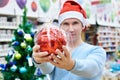 Man in Santa hat holding red ball Christmas tree Royalty Free Stock Photo