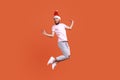 Man in santa hat jumping in the air and looking at camera with positive smile, spreading hands aside Royalty Free Stock Photo