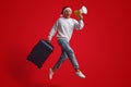 Man In Santa Hat Jumping With Suitcase And Making Announcement With Loudspeaker Royalty Free Stock Photo
