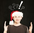 Man in Santa Hat showing his Hands with question marks above his head. Sale Concept Royalty Free Stock Photo