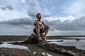 A man sat bent his knees, looking at the sky at the base of the tree and surrounded by water Royalty Free Stock Photo