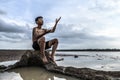 A man sat bent his knees, made a hand symbol to ask for rain at the tree base and surrounded by water Royalty Free Stock Photo