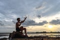 A man sat bent his knees, made a hand symbol to ask for rain at the tree base and surrounded by water Royalty Free Stock Photo