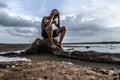 A man sat bent his knees and put his hands on his head, on the base of the tree and surrounded by water Royalty Free Stock Photo
