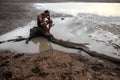 A man sat bent his knees and put his hands on his head, on the base of the tree and surrounded by water Royalty Free Stock Photo