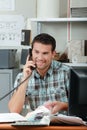 Man sat at desk on telephone holding color charts Royalty Free Stock Photo