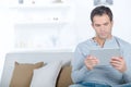 man sat on sofa looking at digital tablet Royalty Free Stock Photo