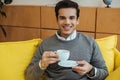 Man with saucer and cup of coffee smiling and looking